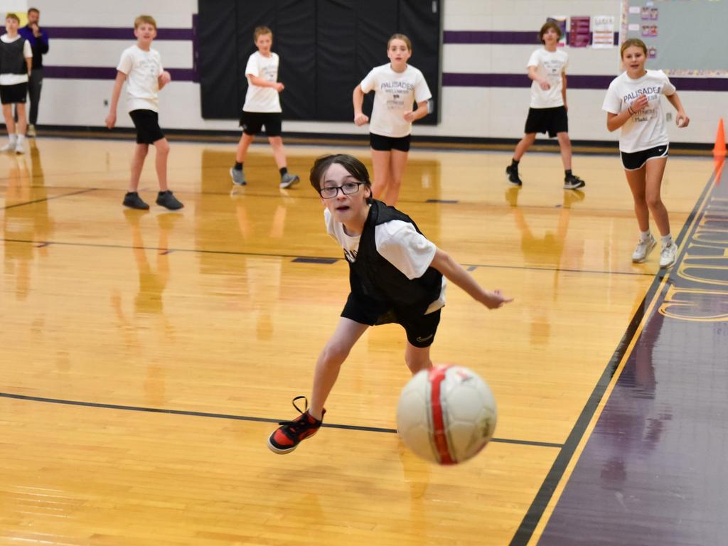 Students playing a game with a ball indoors during gym.