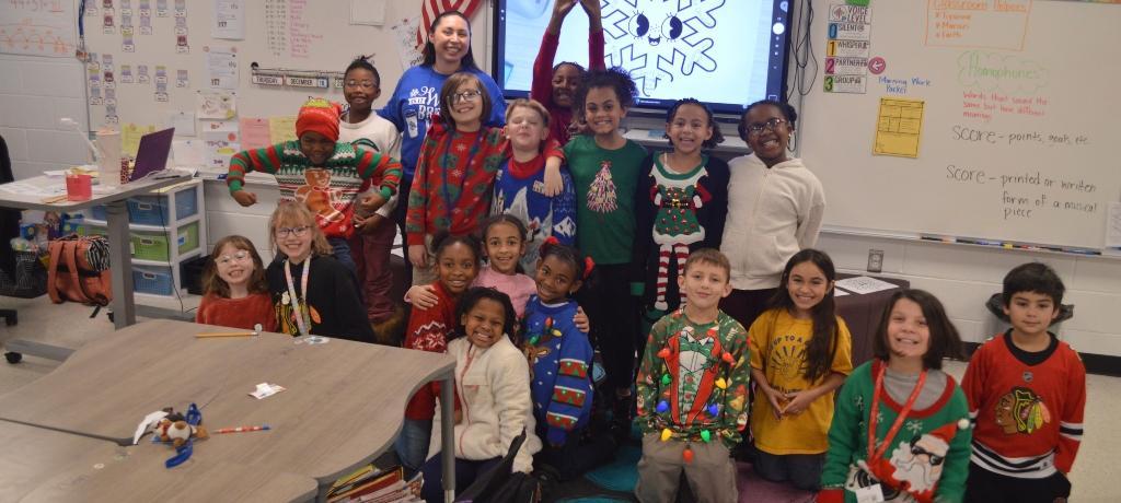 teacher and class of students pose for picture in their holiday sweaters