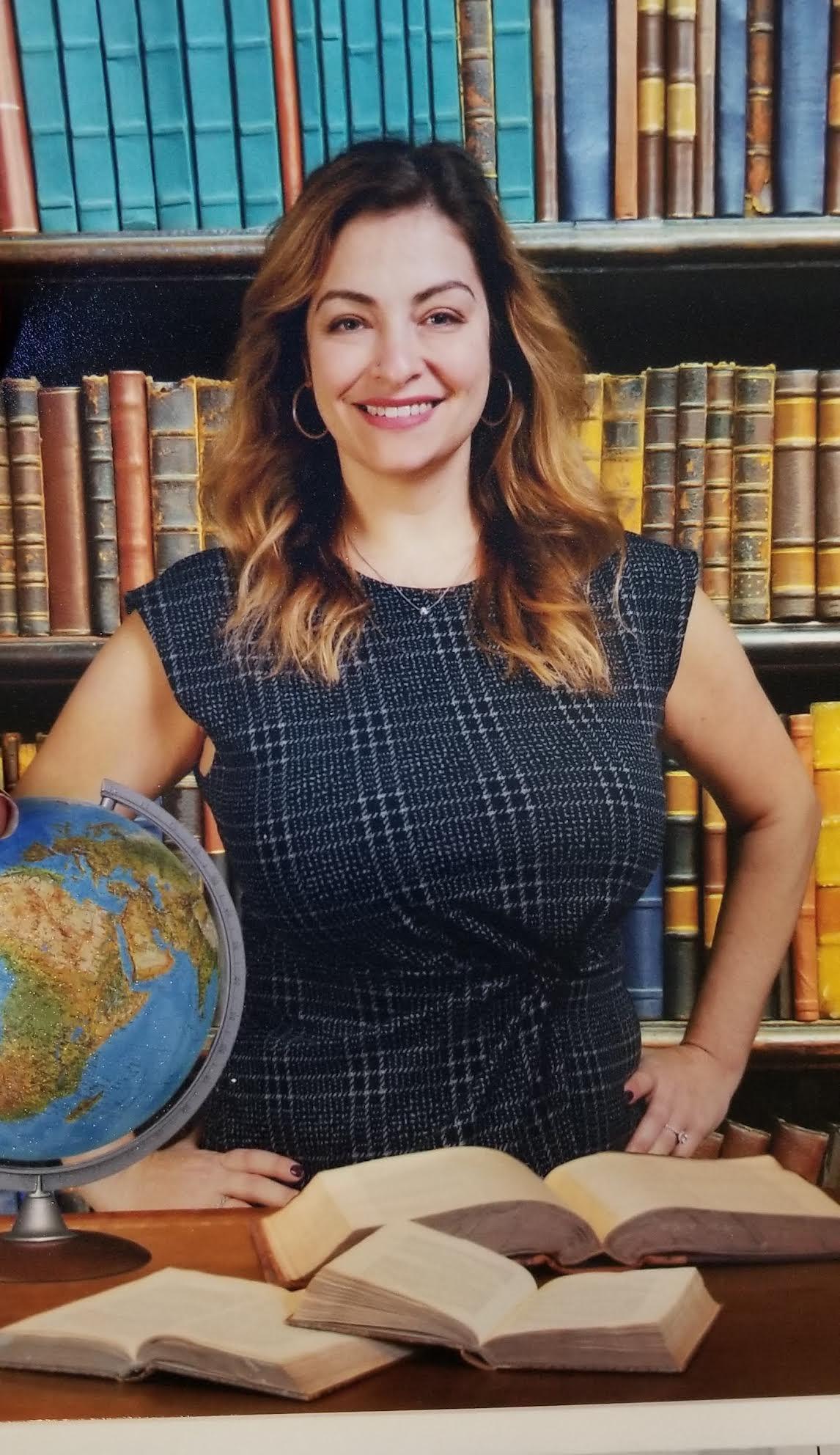 Smiling woman standing in front of library shelf full of books