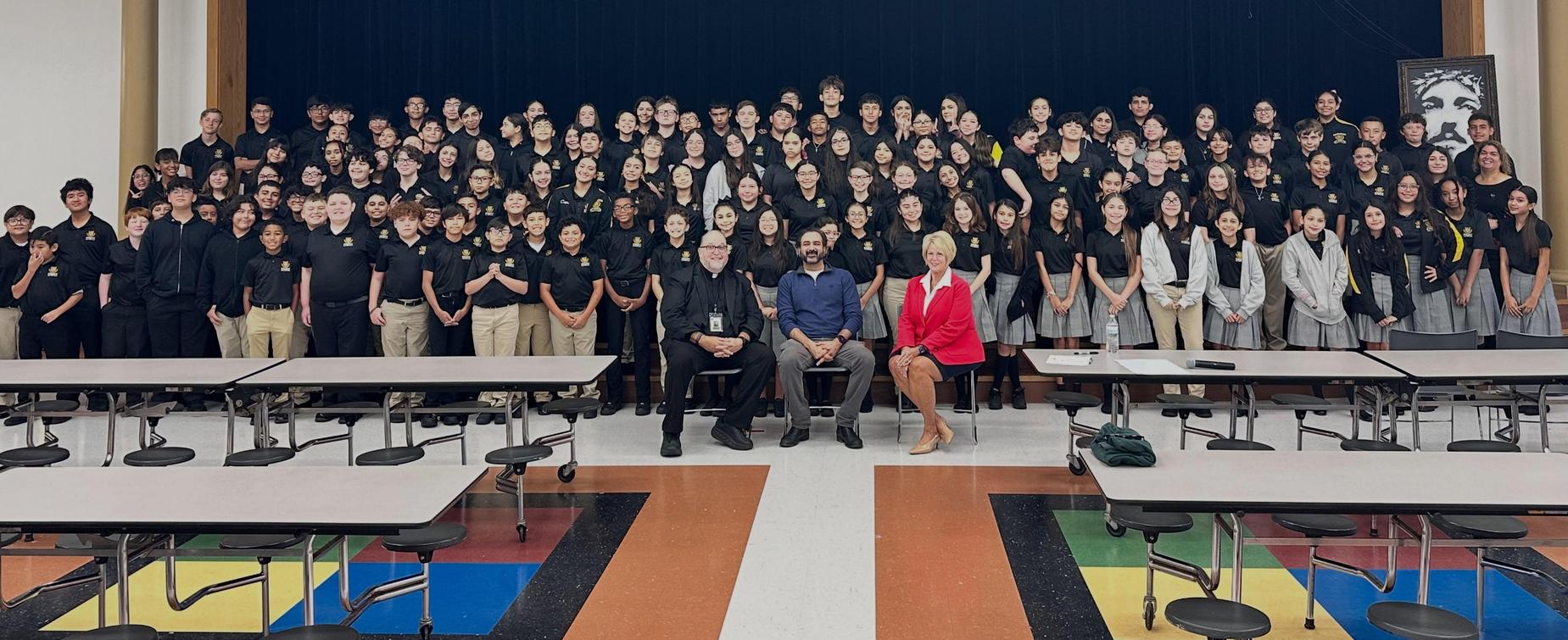 Large group of students and teachers posing together in an auditorium.