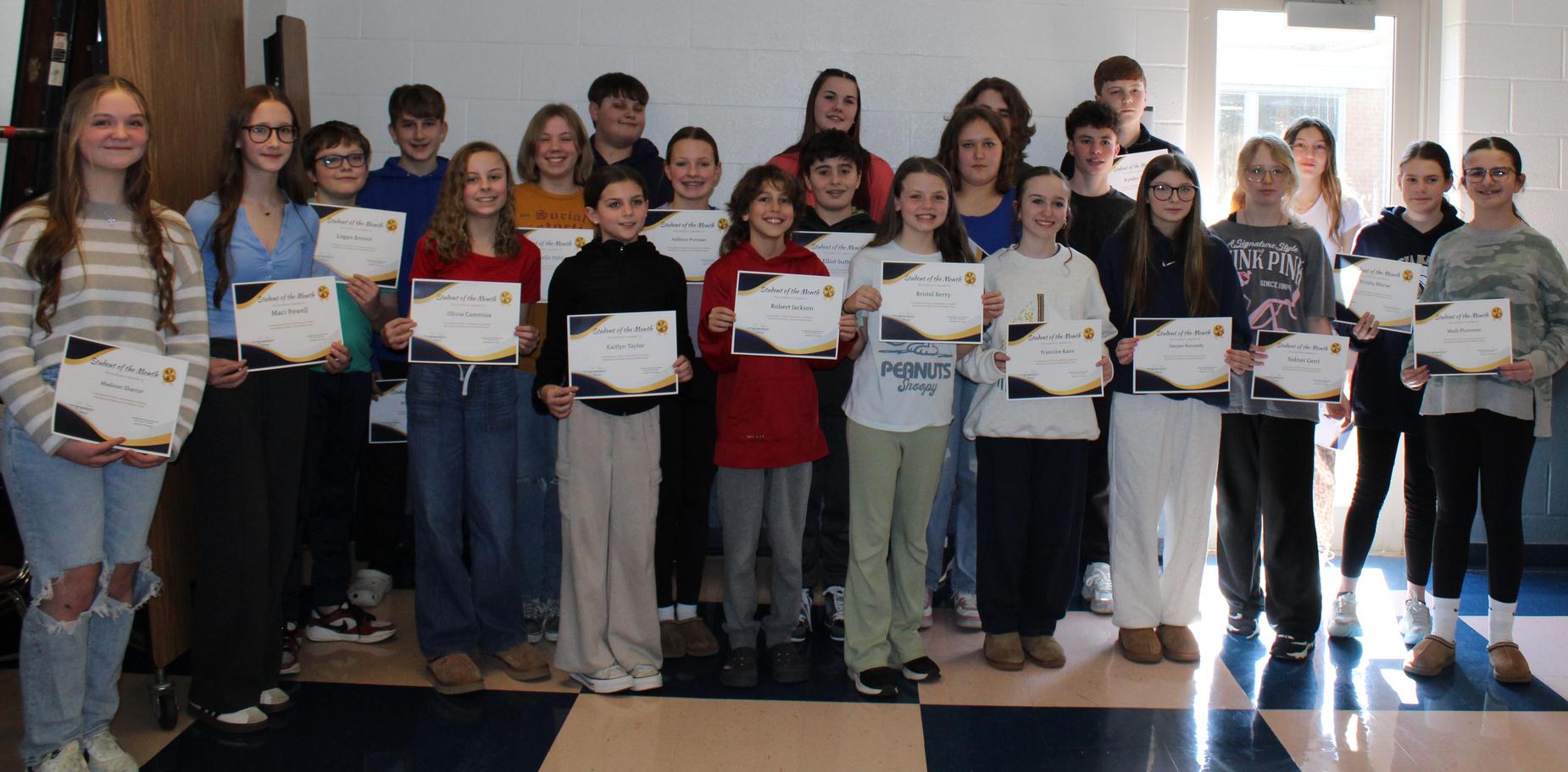 Group of students holding certificates, posing together in a classroom.