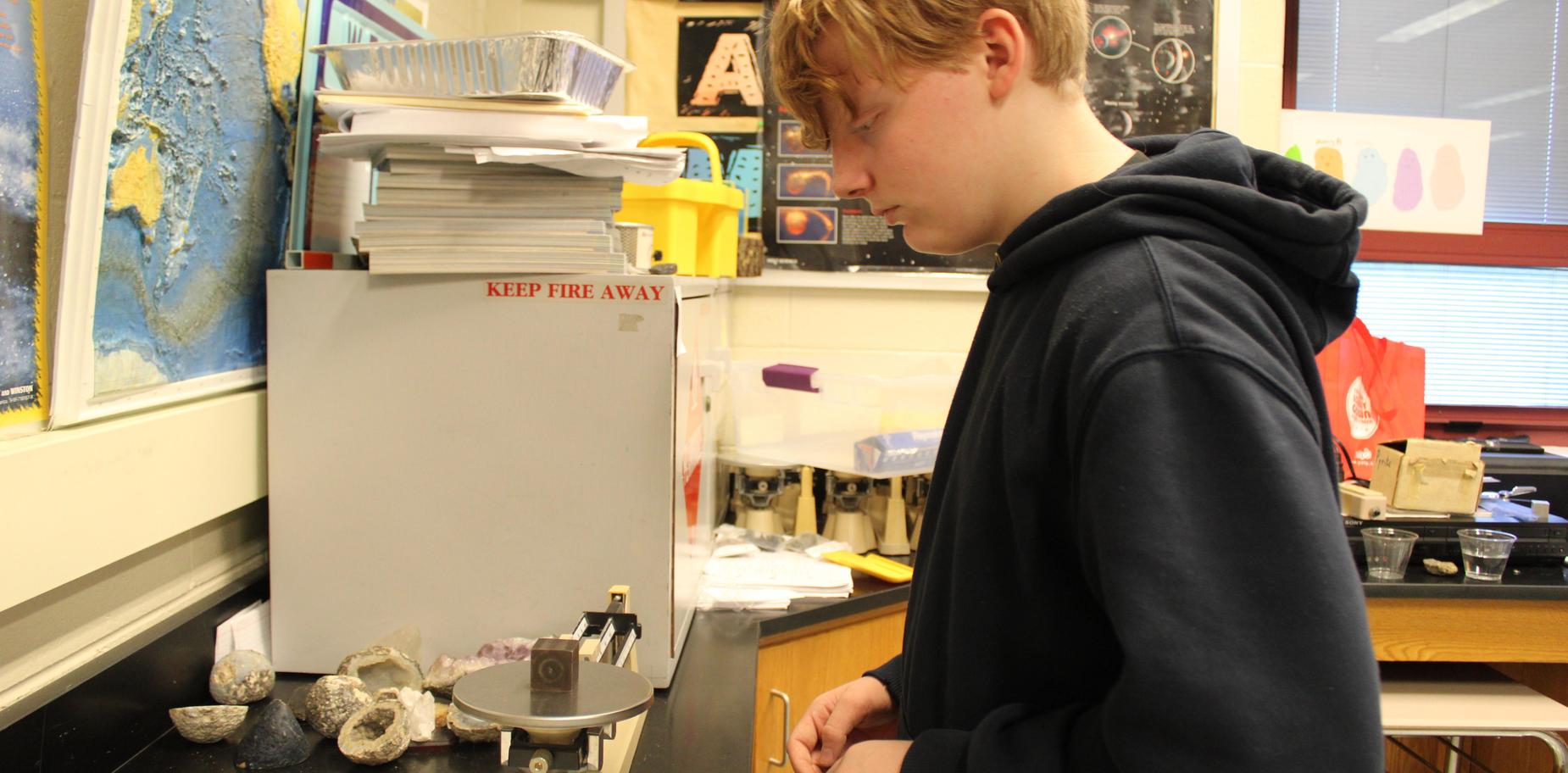 Student working at a lab table, analyzing rocks with a scientific scale.