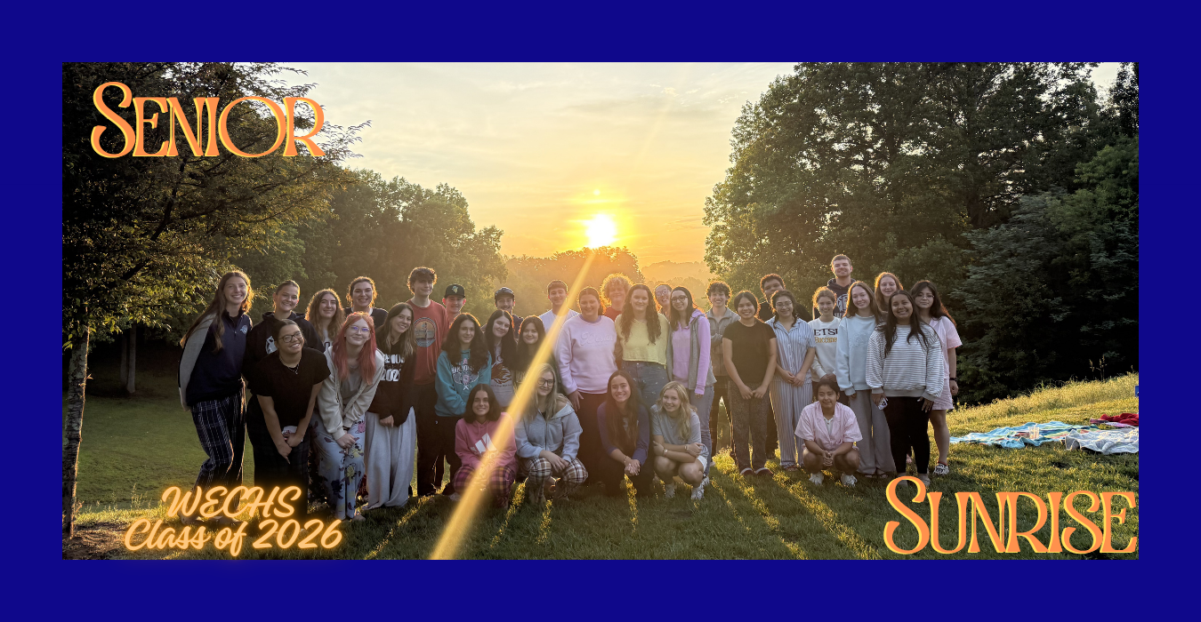 Group of students celebrating sunrise at a graduation event with a large sunset background.