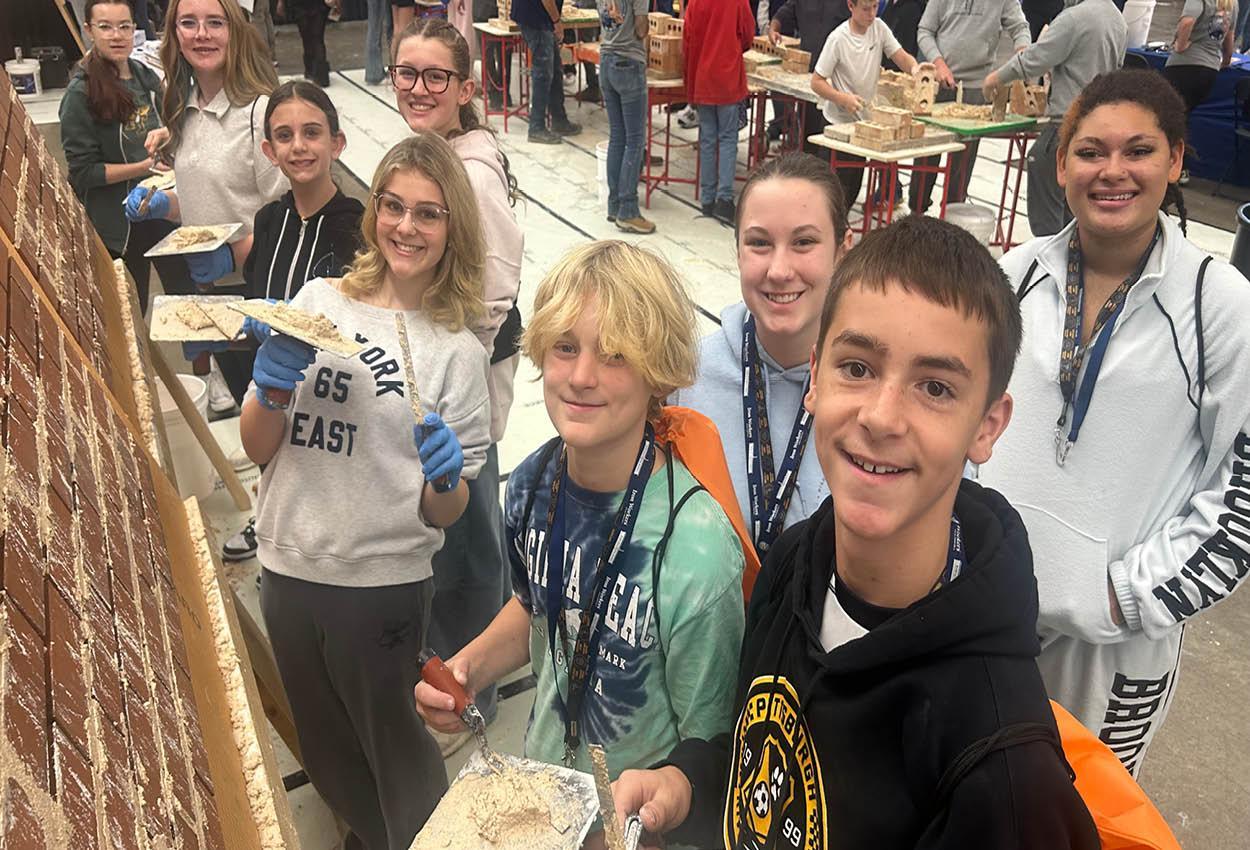 A group of smiling students participating in a hands-on building activity.