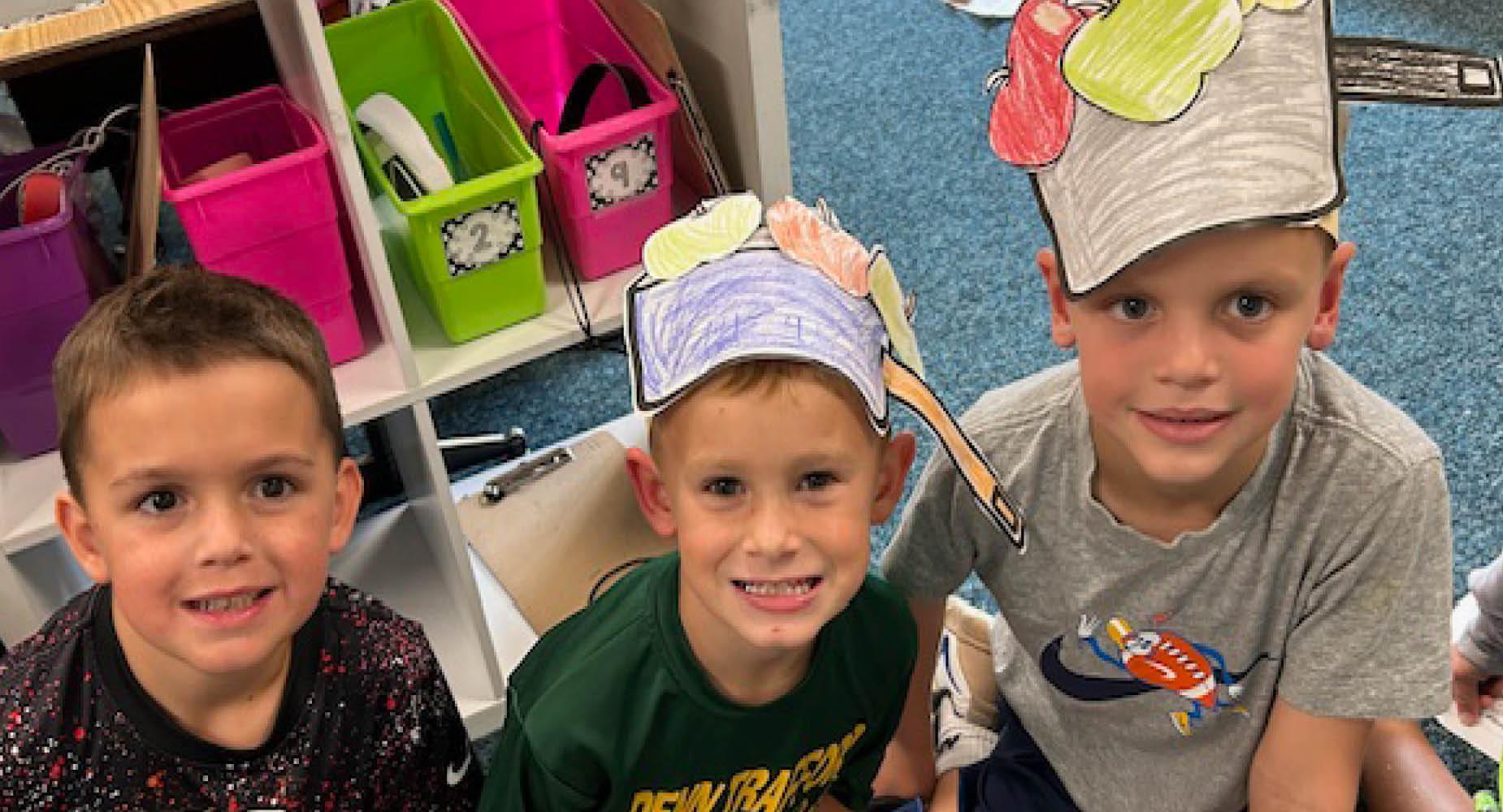 Ashton Fossati, Ryden Rayburg, and Evan Suchy wear apple hats for Johnny Appleseed Day