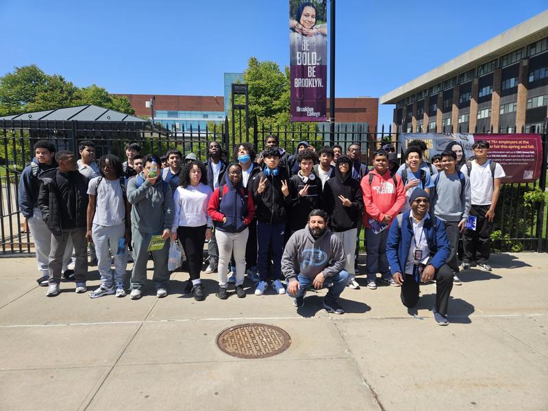 Group of students posing outdoors in front of a school building.