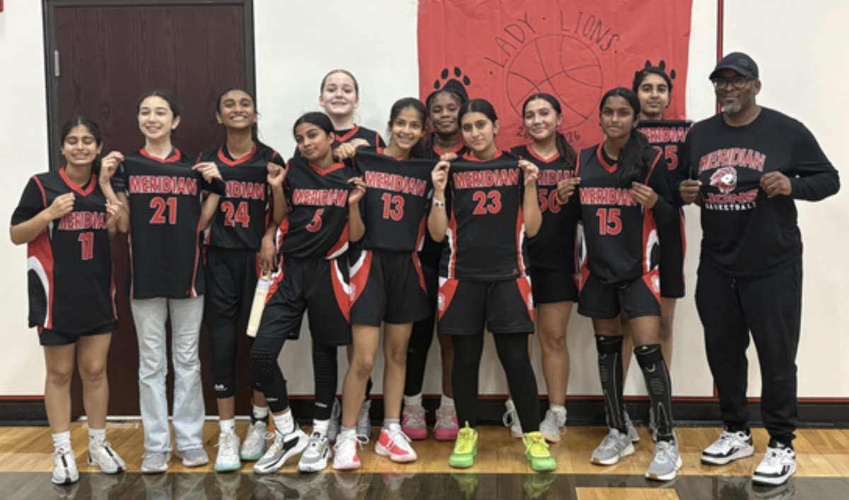 Students stand with their coach, holding up their Meridian uniform shirts