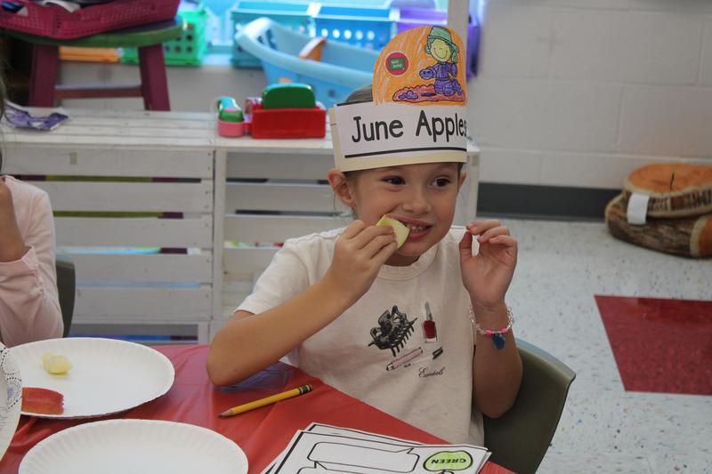 kindergartener biting into apple with apple crown on