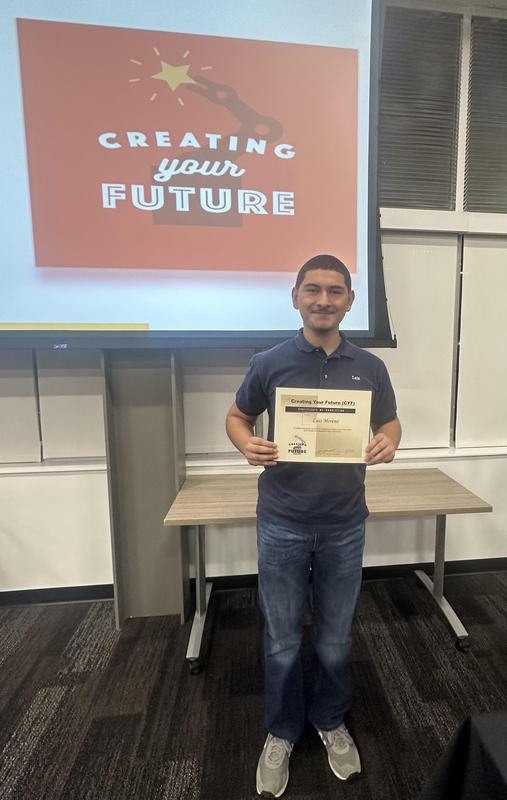 Luis holding up his certificate