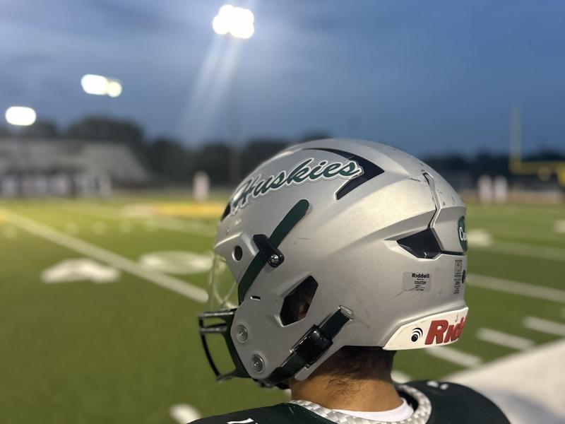 Close-up of a football player wearing a helmet with 'Huskies' printed on it during a game.