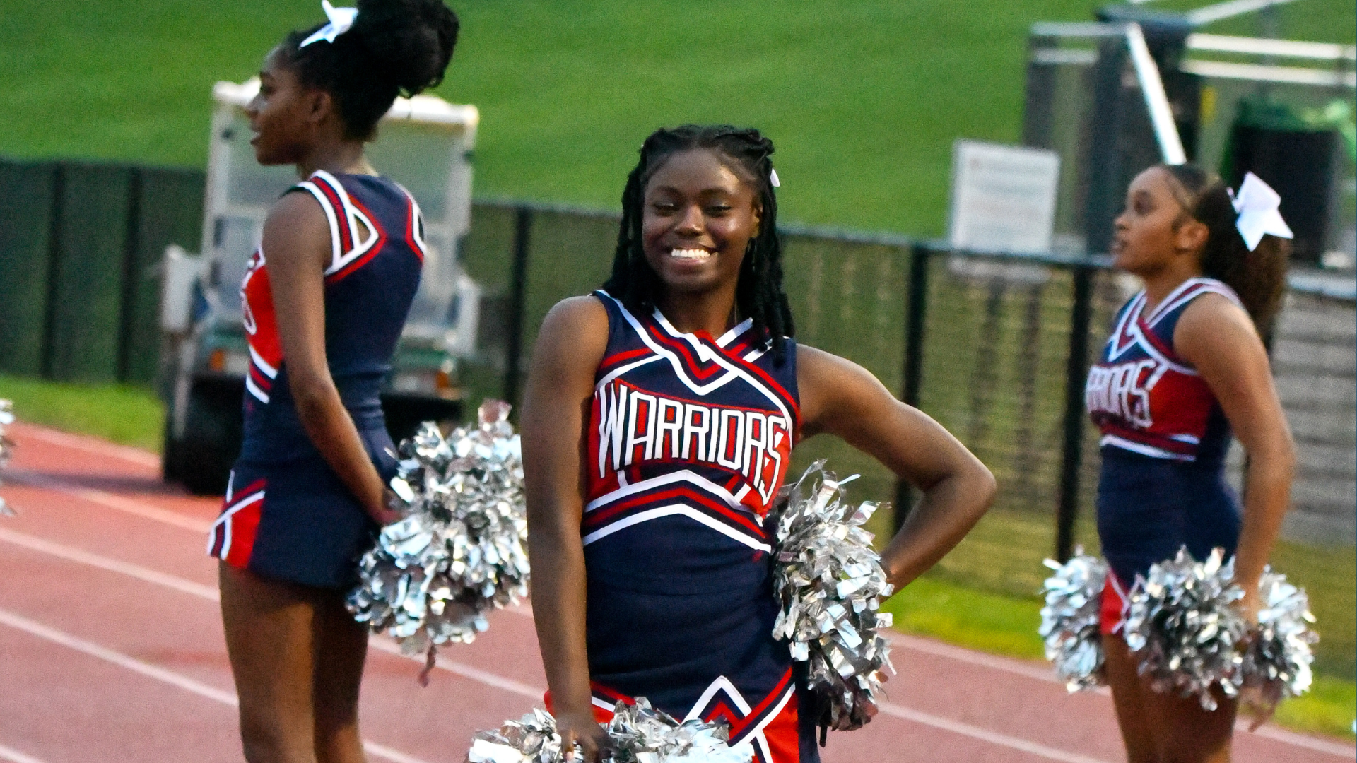 Cheerleaders in uniforms with pom-poms performing at a sports event.