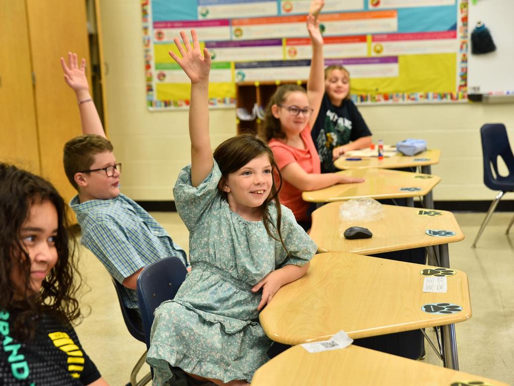 Students raising their hand in a classroom.