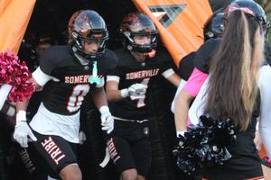 Players running onto the field through an orange tunnel during a game.