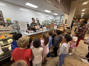 Crestview students watch United bakery employee decorate a cake.