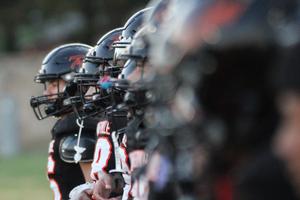 A lineup of football players stands together, focused on the game.