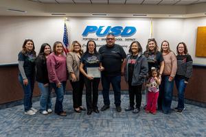 Georgina Torres holds her Teacher of the Year certificate surrounded by colleagues and family at the PUSD Board meeting.