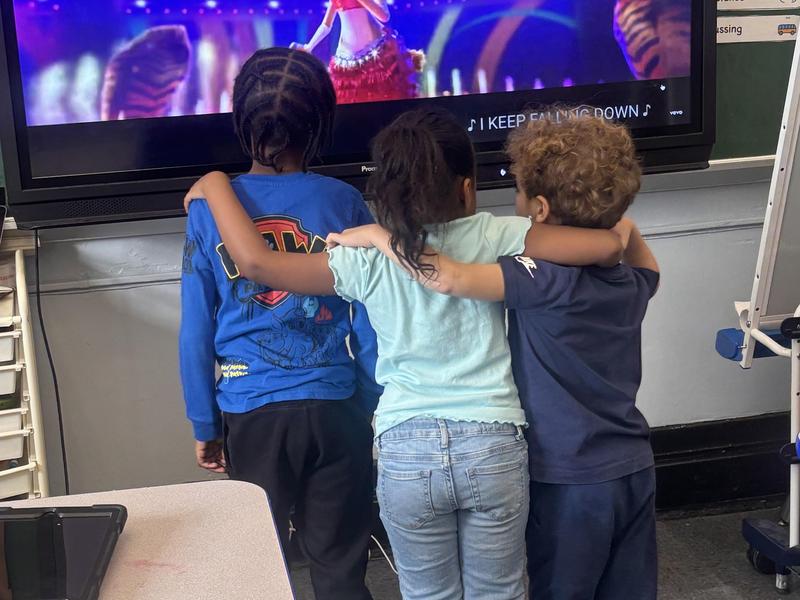 three students standing with their backs to a screen