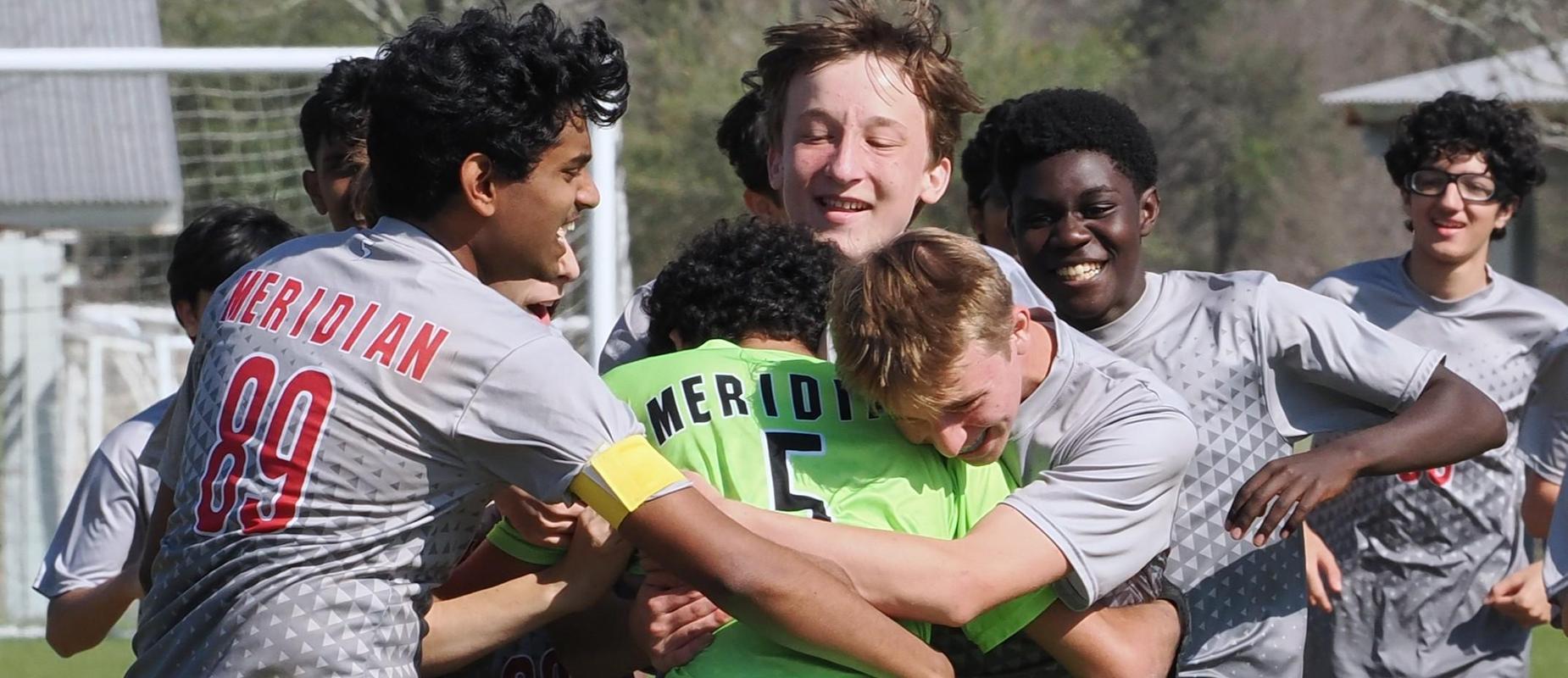 JV Soccer team members run up and hug goalie after a win