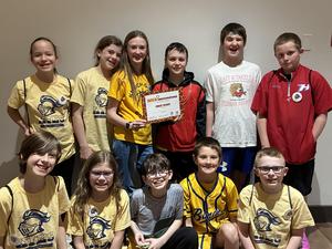 students wearing yellow shirts hold certificate of first place