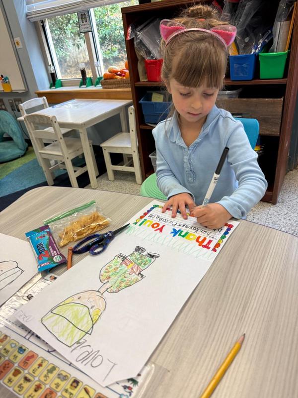 A kindergarten girl works on her thank you card to veterans.
