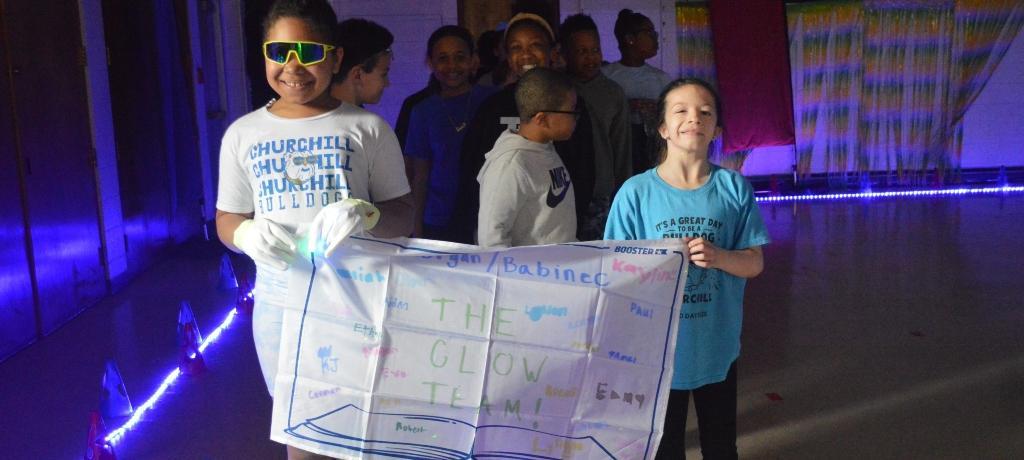 two girls hold classroom banner
