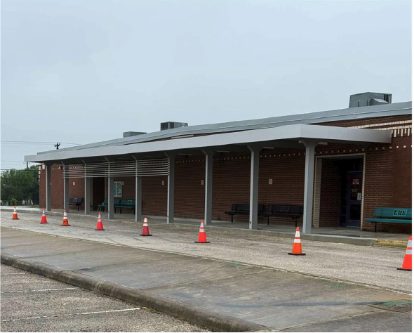 Exterior view of a building with a covered porch and traffic cones.