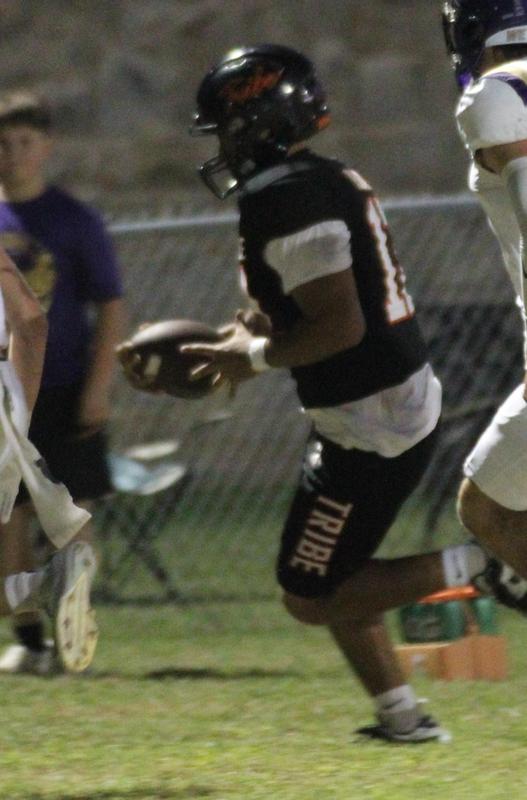 A football player in a black uniform running with the ball on a field.