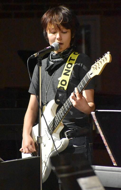Boy playing electric guitar and singing with a microphone.