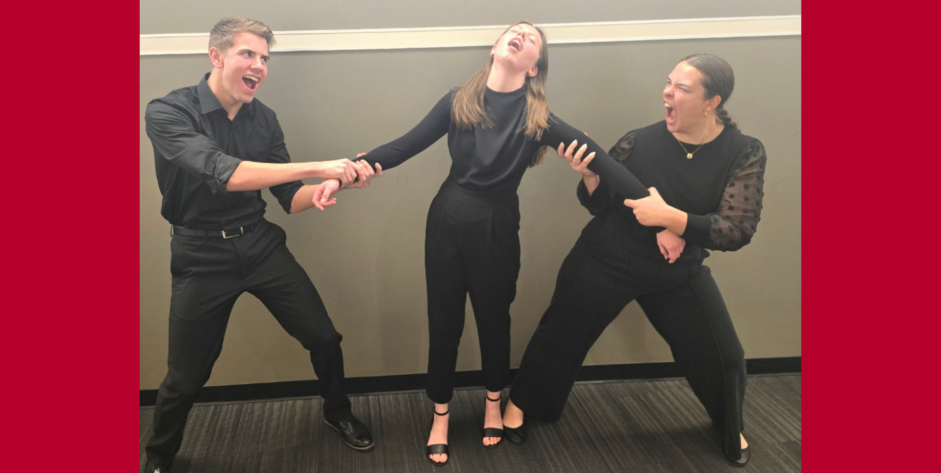 Three individuals in black outfits striking dramatic poses against a red backdrop.
