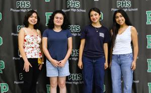 Four Pioneer High School students pose for a photo in front of a Pioneer High School backdrop, smiling at the camera.
