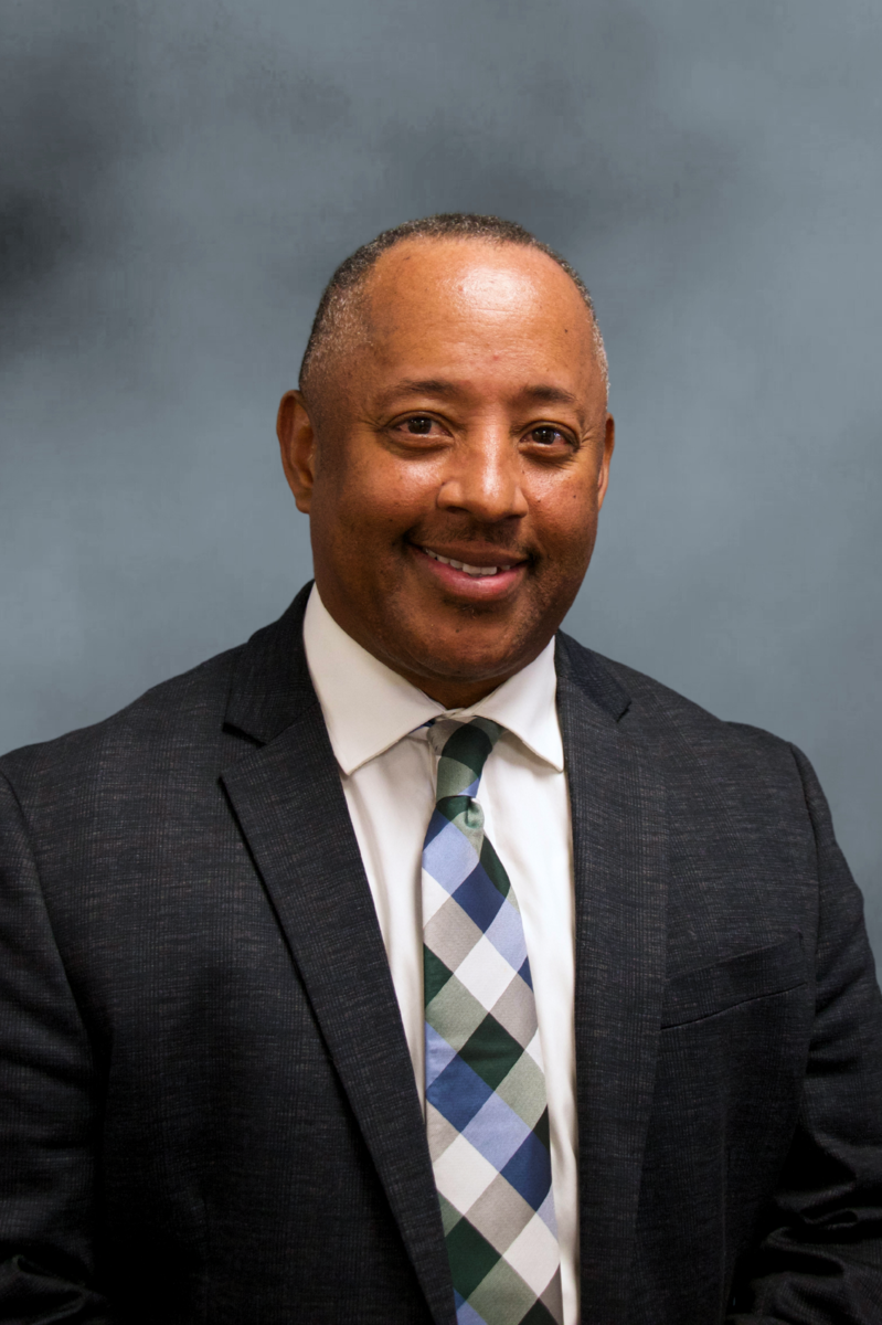Dr. Sylvester with short cropped hair and a suit jacket