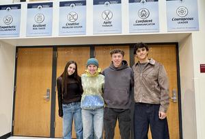 Four Durango High School students stand in front of Portrait of a Graduate posters