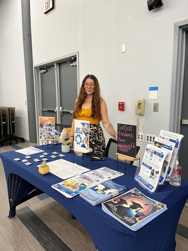 woman standing next to table handing flyers