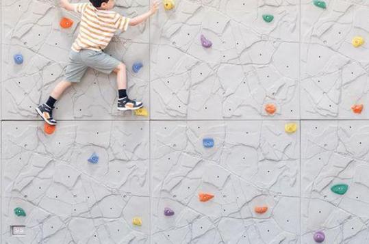 Child climbing a colorful indoor rock wall.