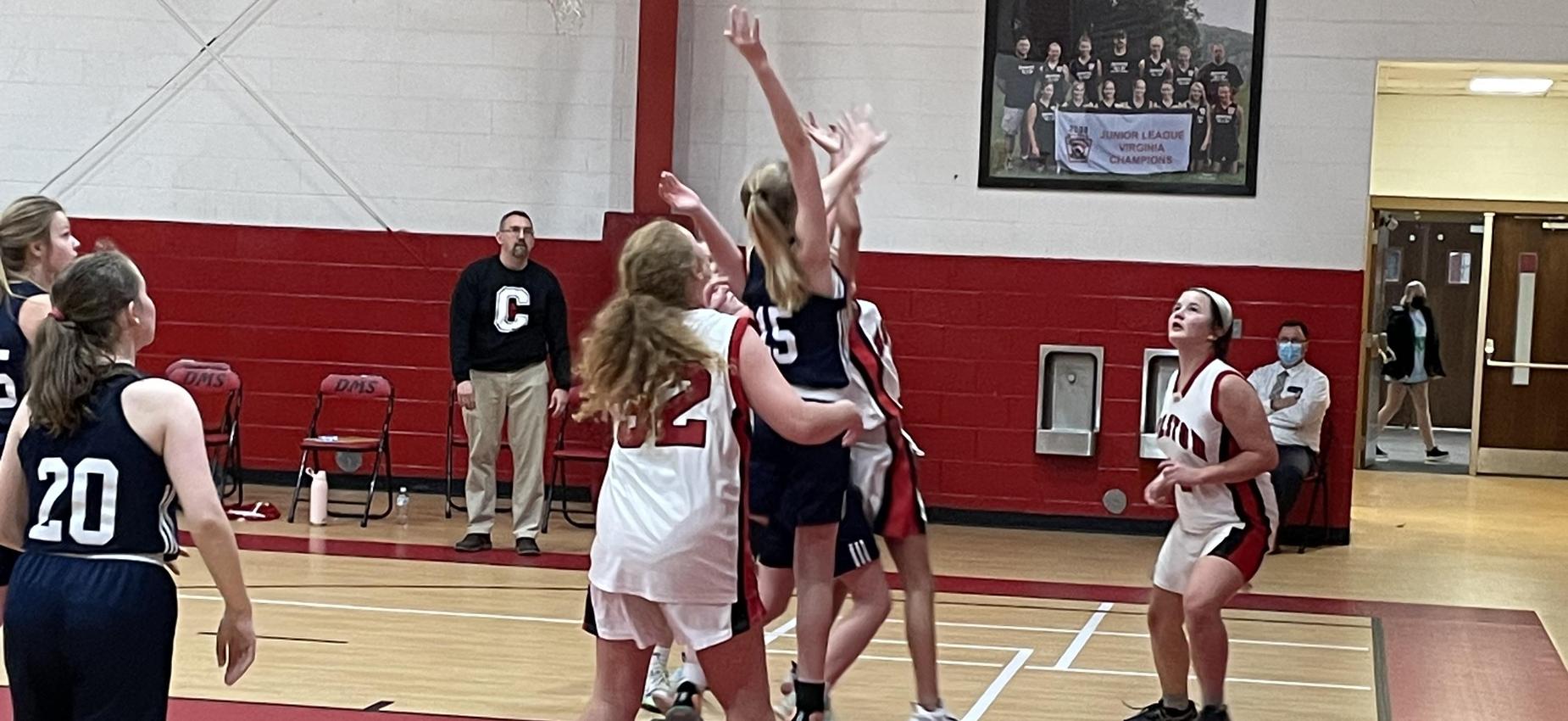 Basketball players wait for a rebound in a gym.