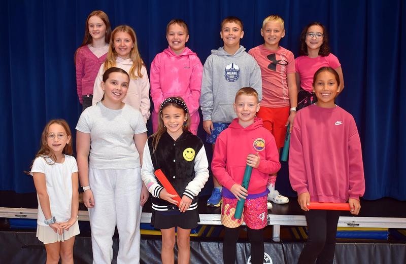 A group of children posing together, smiling, on a stage backdrop.