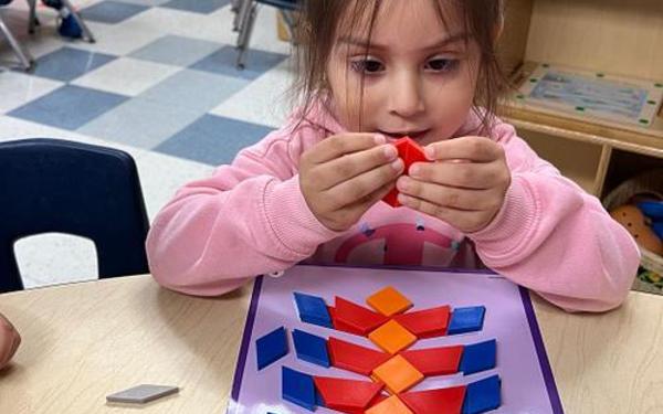 Girl working with pattern blocks.