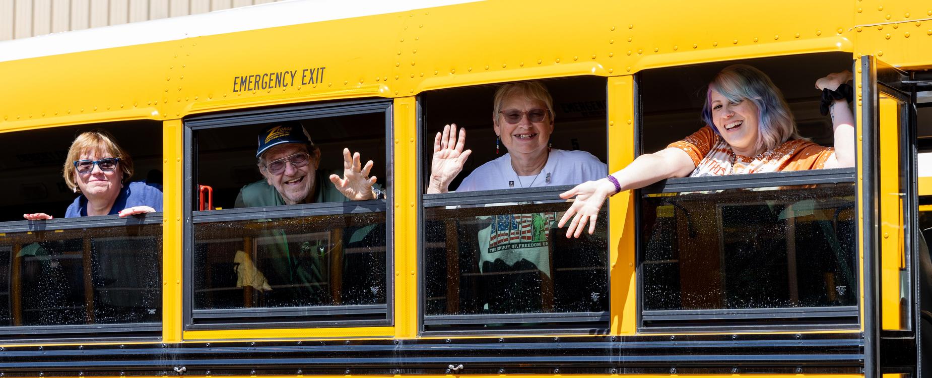 Bus drivers waving from windows.