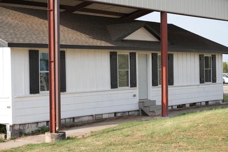 A white building with black shutters under a metal roof.