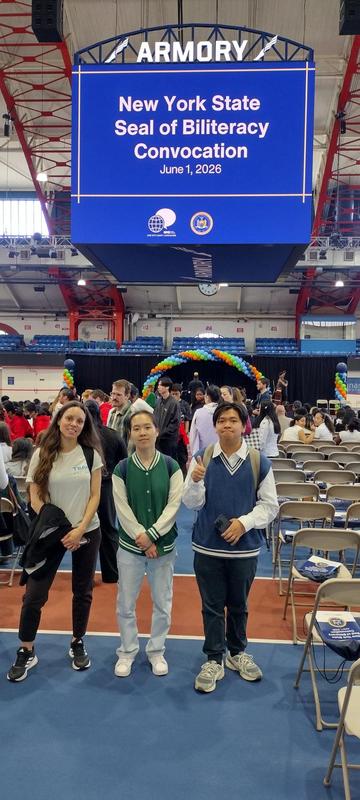 Three students pose in front of a stage at a convocation event.