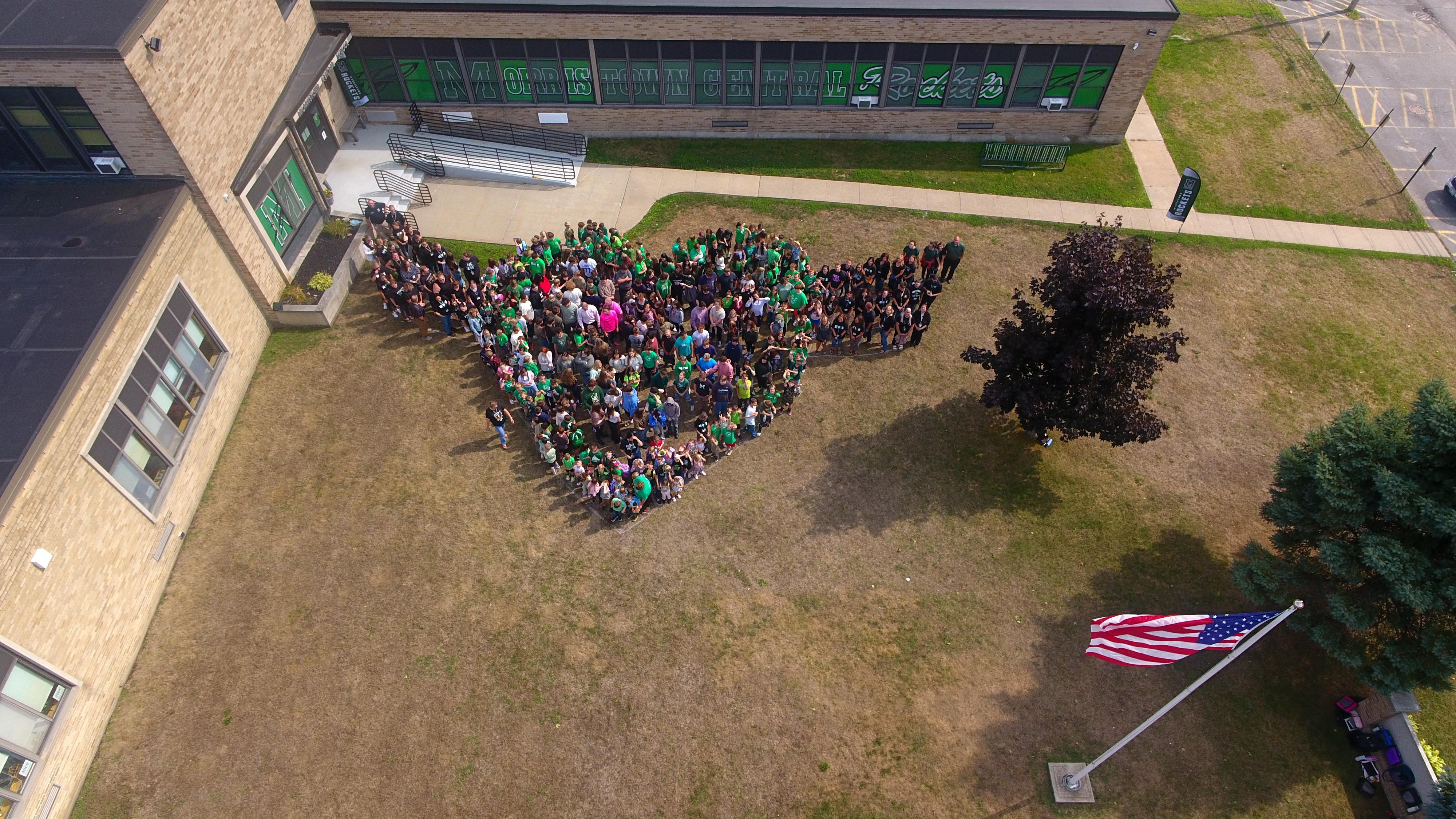 MCS students form a heart in the lawn.