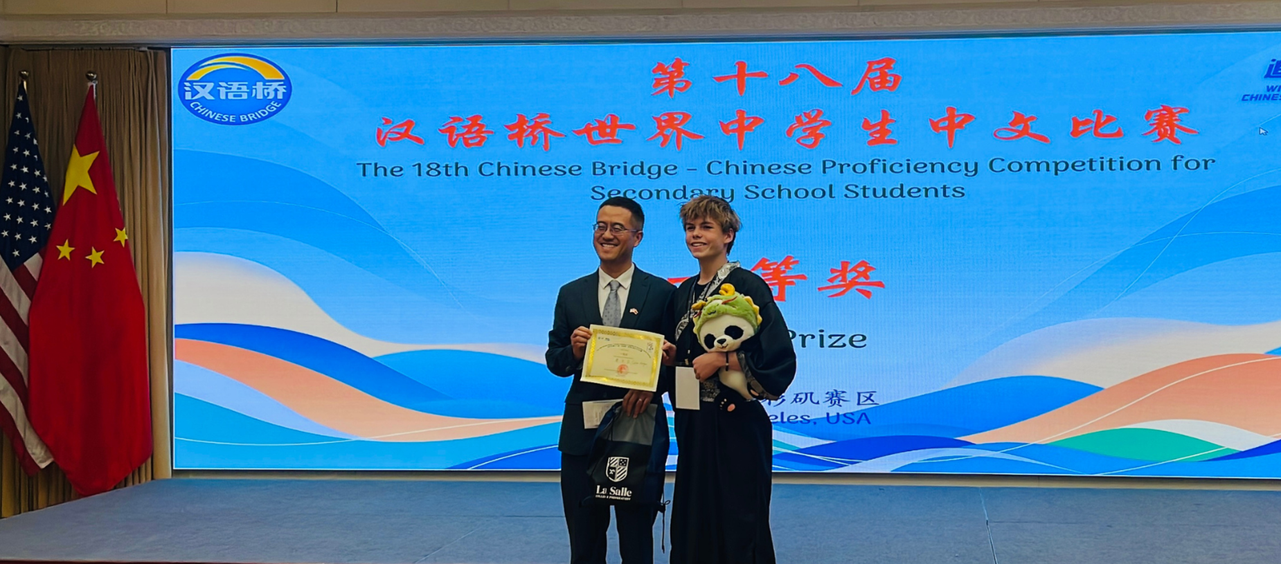 Two students in formal attire holding a certificate in a presentation setting.