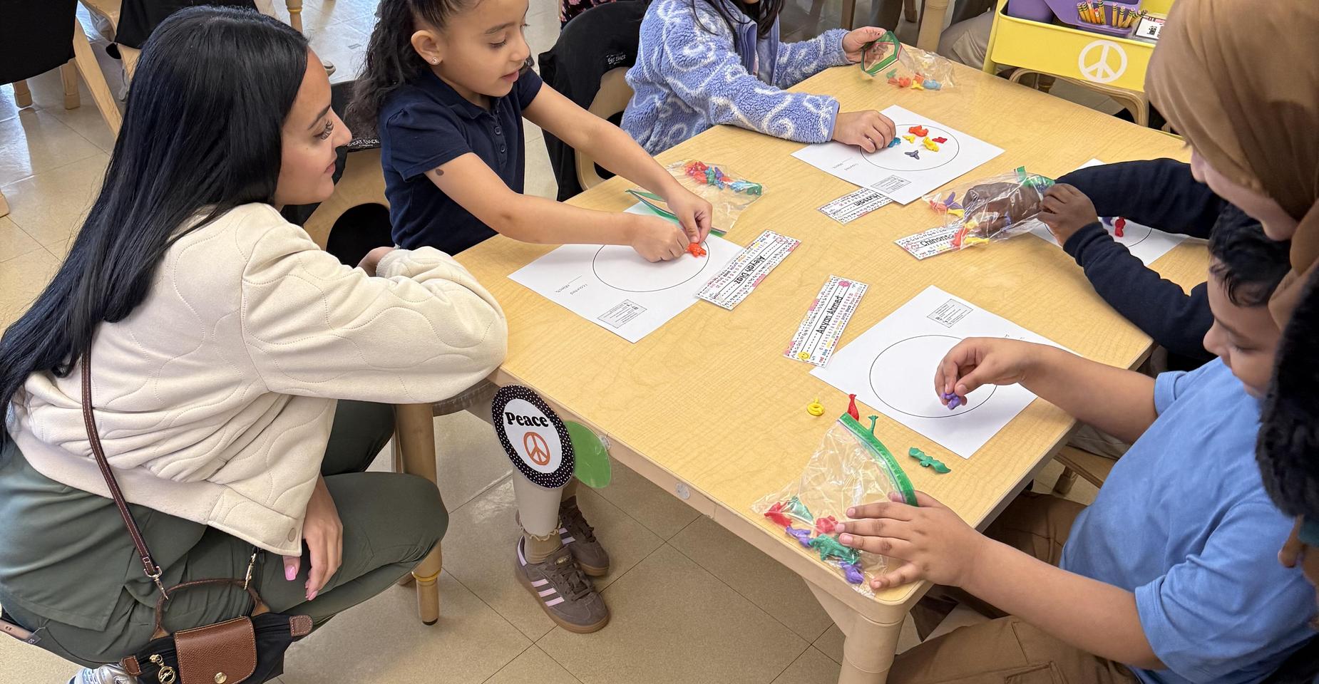 Children and adults engaging in a hands-on activity at a classroom table.