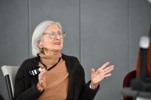 Magda Bader with her hands outstretched as she talks with students