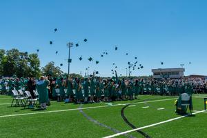 graduates toss their caps into the air