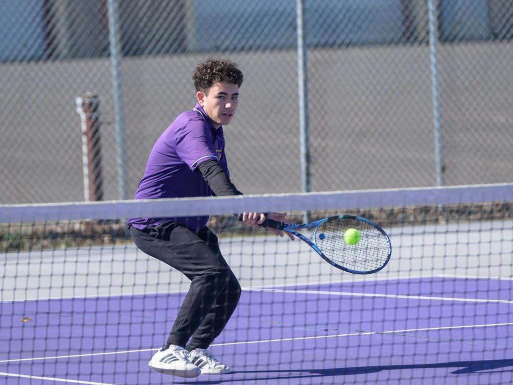 A Tennis Team athlete hitting a tennis ball in front of the net.