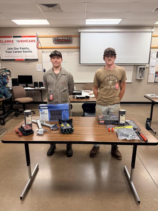 two students standing behind a small table with tools