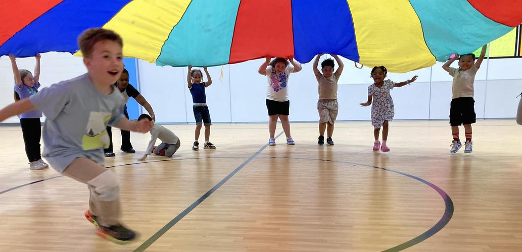 kindergarteners playing under the parachute