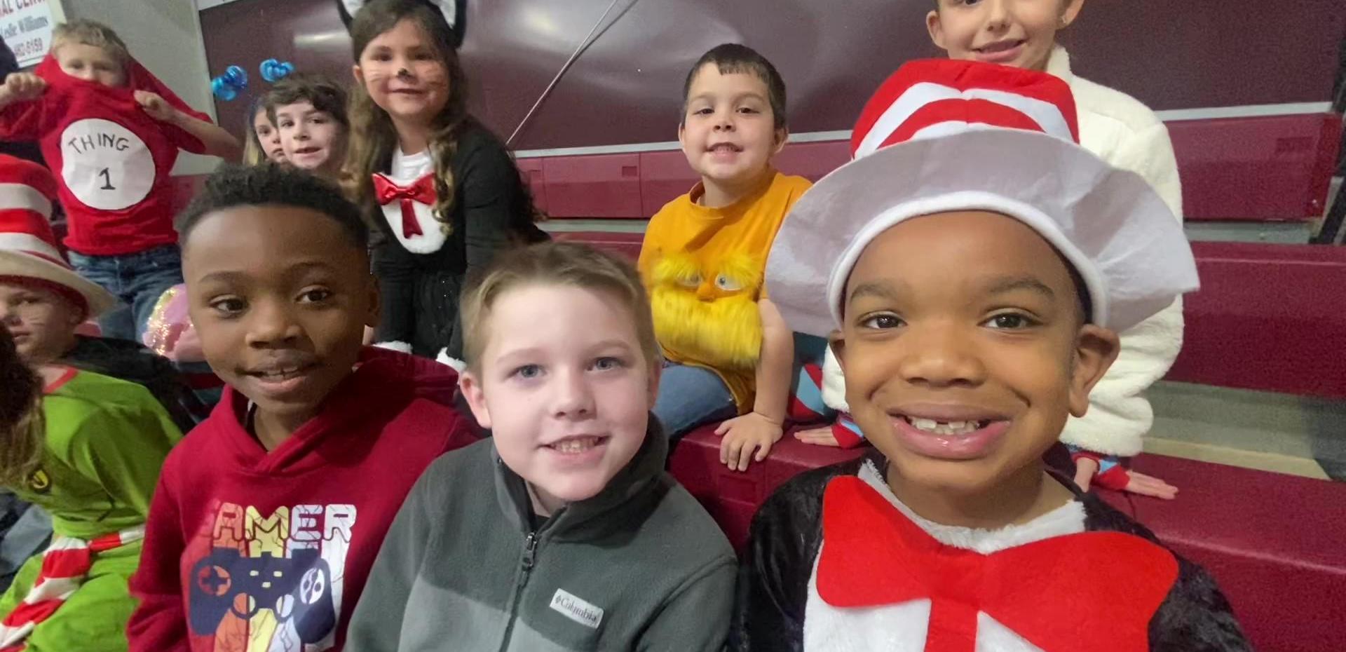 A group of children in costumes smiling together at an event.
