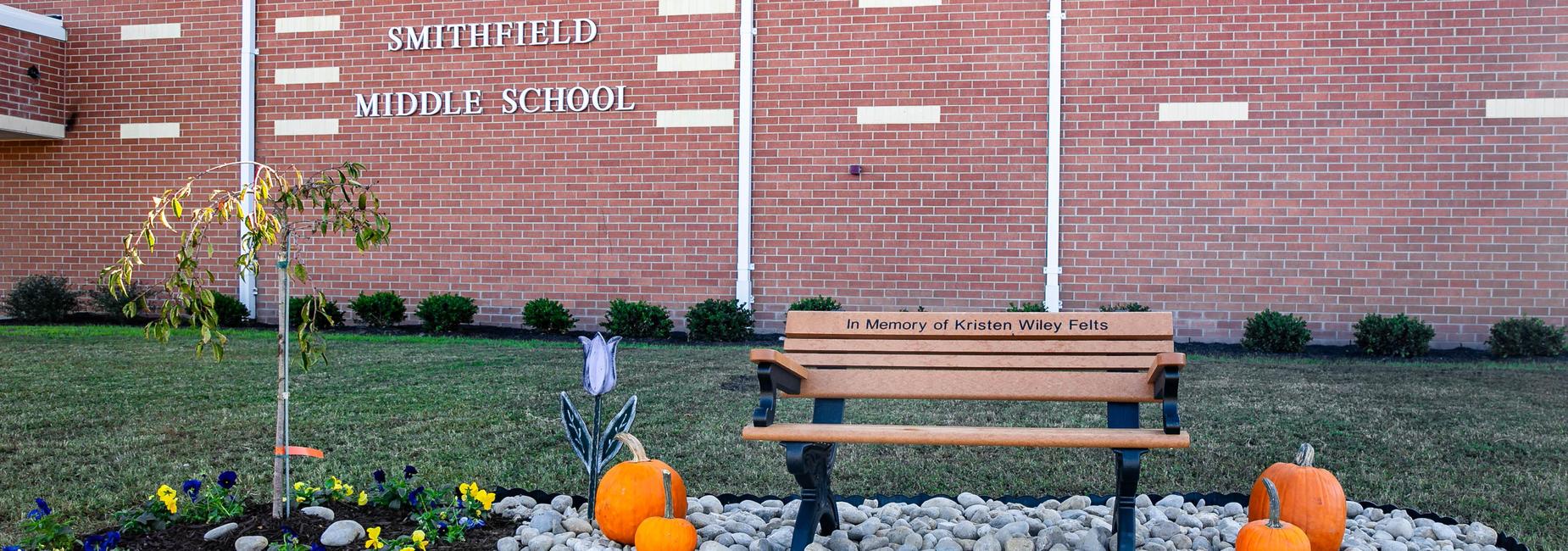 Smithfield Middle School sign with a memorial bench and seasonal decorations.